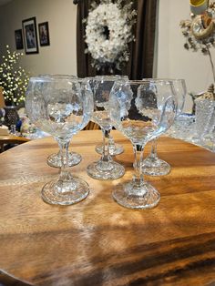 four wine glasses sitting on top of a wooden table