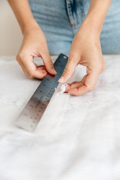 a woman is measuring the length of her bed sheet with a tape measure on it