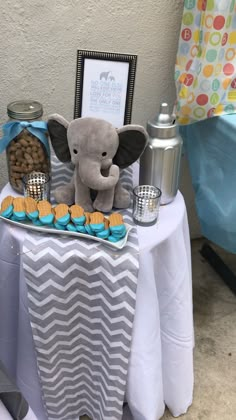 an elephant themed baby shower table with cookies and cupcakes on the table next to it