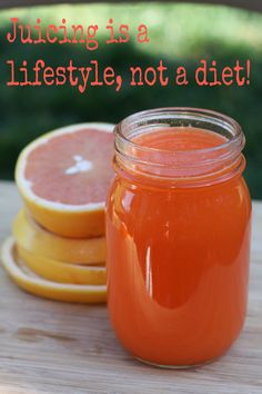 a jar filled with orange juice sitting on top of a wooden table next to sliced grapefruit