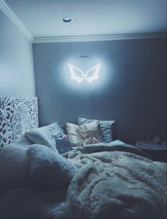 a bedroom with a butterfly light on the wall above the bed and pillows in front of it