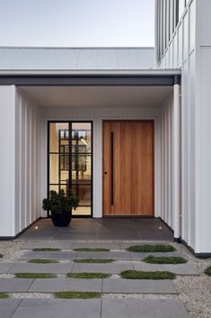 the front entrance to a modern home with grass growing on the walkway and potted plants