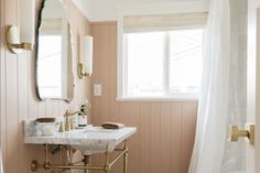 a bathroom with pink walls and gold fixtures