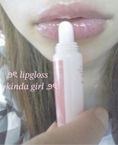 a girl is holding a lip gloss in her hand