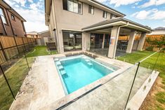 a pool in the middle of a yard with a fence around it and a house behind it