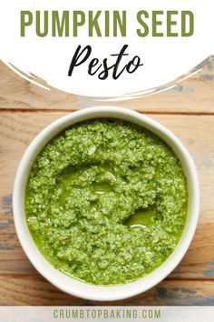 a white bowl filled with green pesto on top of a wooden table