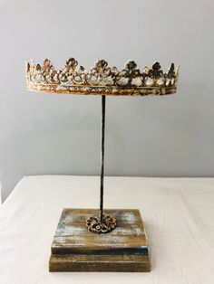 a gold crown sitting on top of a wooden stand next to a white tablecloth