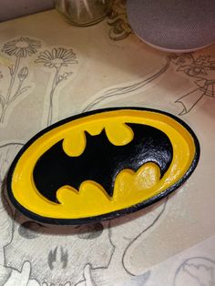 a yellow and black batman badge sitting on top of a table