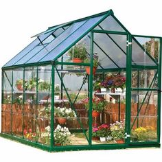 a small green house with flowers in it