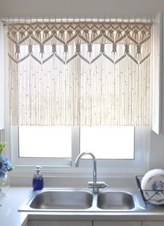 a kitchen sink under a window covered in bamboo blinds