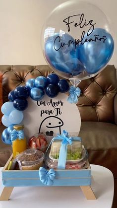 a table topped with balloons and food on top of a white table covered in blue ribbon