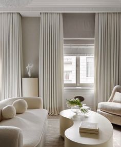 a living room filled with white furniture and curtains