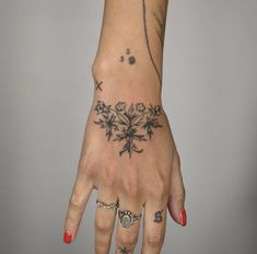 a woman's hand with tattoos on it and flowers tattooed on the middle finger