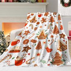 a christmas themed blanket sitting on top of a white couch next to a fire place