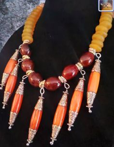 Another piece from my private vault. Big and rich brown porcelain beads are spaced with silver aurora borealis rhinestone rondelles which flank very ornate Tibetan orange resin dangles. The sides of the necklace are comprised of yellow African recycled glass rondelles with the back having African lost wax brass beads, silver tone daisy spacers and silver tone metal bi-cones. The back is finished with silver tone hardware, a fancy hook and a 3" extender chain with a vintage ethnic coin. Adjusts from 20-23" and is lightweight and comfortable to wear. Perfect for your Fall wardrobe or anytime when worn by a woman of color. OOAK Wearable Art from the Atelier of Kat Kouture. This is a very rich, posh and elegant piece. (the dangles are 3" in length and approximately 3/4" in width) Brown Artisan Jewelry With Dangling Beads, Artisan Brown Jewelry With Dangling Beads, Orange Resin, Jewellery Shop Design, Big And Rich, Turquoise Western, Porcelain Beads, Brass Beads, Western Jewelry