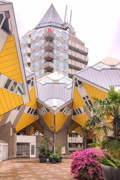 an unusual building in the middle of a courtyard with potted plants and flowers around it