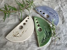 three ceramic pieces with holes in them sitting on a table next to a plant branch