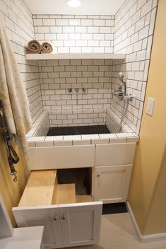 a bathroom with white tile and wooden drawers