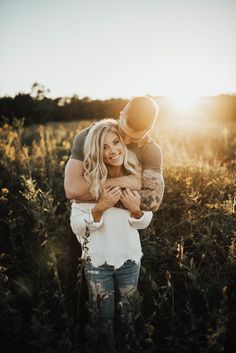 a man and woman hugging in the middle of a field