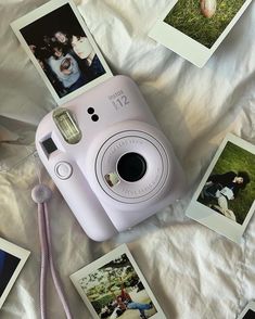 a pink camera sitting on top of a bed next to pictures