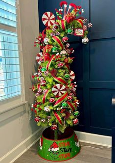 a christmas tree decorated with candy canes and candies in a green tin can