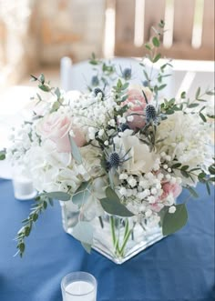 a vase filled with white and pink flowers on top of a blue table cloth