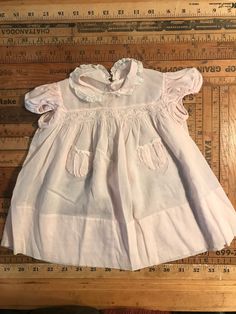 This is the most precious baby dress, pale pink cotton, with white lace and embroidered flowers on collar, and petite smocking on chest.  No tags, could be handmade, but if so by a highly skilled seamstress.  Sz. Is small 3-6 mo. I would say. Pink Cotton Dress With Doll Collar, Pink Vintage Short Sleeve Dress With Lace Trim, Pink Vintage Dress With Lace Trim And Short Sleeves, Vintage Pink Dress With Lace Collar, Cute Pink Dress With Lace Collar, Pink Cotton Collared Dress, Pink Collared Cotton Dress, Pink Smock Dress For Baptism, Vintage Smock Dress For Daywear