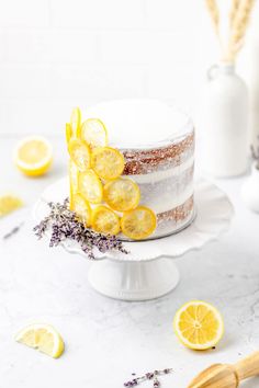 a cake with lemon slices and lavender sprinkles is on a white pedestal