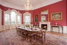 a large dining room with red walls and white trim