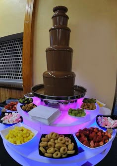 a table topped with lots of desserts next to a tall chocolate fountain filled with water