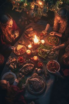 people sitting at a table with food and candles in front of them, surrounded by christmas trees