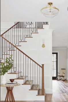 a staircase leading up to a living room with a table and chair in front of it