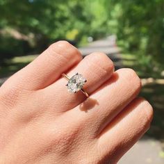 a woman's hand holding a diamond ring in the middle of her left hand