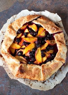 a pie with fresh fruit on it sitting on top of a piece of parchment paper