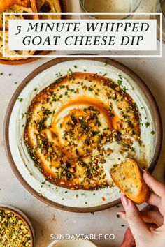 a white plate topped with cheese dip next to bread and other food on a table