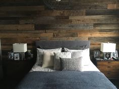 a bedroom with wood paneling on the wall and bed in the foreground, two nightstands at the end