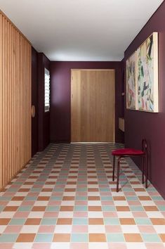 an empty room with two chairs and paintings on the wall, in front of a door