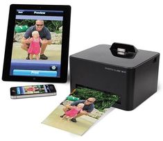 a digital photo printer next to an ipad and cell phone with pictures on the screen