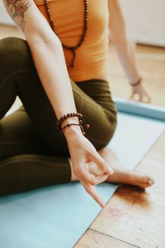 a woman sitting on a yoga mat with her hand in the air