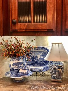 a blue and white vase sitting on top of a kitchen counter next to a lamp