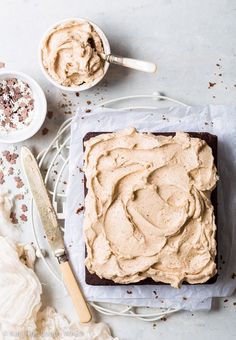 a cake with frosting sitting on top of a white plate next to two bowls