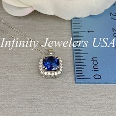 "The pendant pictured is a lab created blue sapphire and moissanite halo #6302 -Approximate total carat weight: approx. 1.90ctw diamond equivalent -Center Stone Size: 7x7mm - approx. 1.70ct diamond equivalent -Center Stone Shape: cushion cut -Gem Type: lab created sapphire -Stone Clarity: VS2 -Stone Color: Blue -Moh's Scale: 9 hardness -Accent Stone Size: 20 round approx. 0.20ct. diamond equivalent -Gem Type: moissanite -Stone Clarity: VS2 -Stone Color: FG -Moh's Scale: 9.5 hardness -Metal Type Sapphire Necklaces With Halo Setting, Halo Design Tanzanite Jewelry For Anniversary, Tanzanite Jewelry With Halo Design For Anniversary, Tanzanite Halo Design Jewelry For Anniversary, Blue Necklace With Halo Setting For Gift, Tanzanite Jewelry With Halo Design And Round Cut, Anniversary Sapphire Necklace With Lab-created Sapphire, Anniversary Sapphire Necklace With Lab-created Gem, Round Cut Tanzanite Jewelry With Halo Design