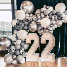 the number twenty two made out of silver and white balloons is displayed in front of a blue curtain