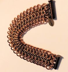 Handcrafted of bronze and copper, our luxe cuff-style bracelet offers a captivating combination of classic European 4-in-1 weaving and contemporary style. An eye-catching shimmer of warm gold provides a touch of refinement, guaranteeing this stylish statement piece will get lots of attention. 16 gauge bronze and copper jump rings woven with the bronze center stage flanked by copper rings. Shown here in the first three photos with light to deeper color backgrounds to highlight the subtle contrast in the metals.Finished with an antique copper magnetic slide clasp.Measures 7 inches overall. * Signature SUZANNA charm. * Arrives in a black satin drawstring storage pouch. * To inquire about this product please click Ask a Question on our website or convo on our Etsy Shop. * In stock and ready to Chain Maille Bracelet, Color Backgrounds, Chainmaille Bracelet, Chain Maille, Copper Rings, Storage Pouch, Deep Colors, Braided Bracelets, Center Stage