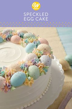 a cake decorated with eggs and flowers on top of a white platter next to utensils