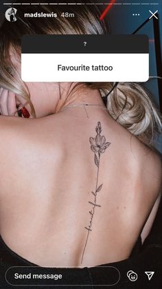 the back of a woman's neck with a flower tattoo on her left shoulder