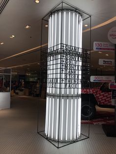 a tall metal object in the middle of a mall floor with people walking around it