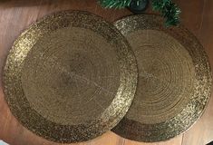 two round placemats sitting on top of a wooden floor next to a potted plant