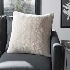 a couch with a pillow on top of it next to a side table and window