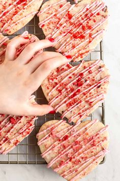 someone is holding onto some cookies that are covered in pink icing